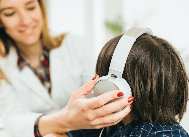 woman putting headphones on a hearing loss patient