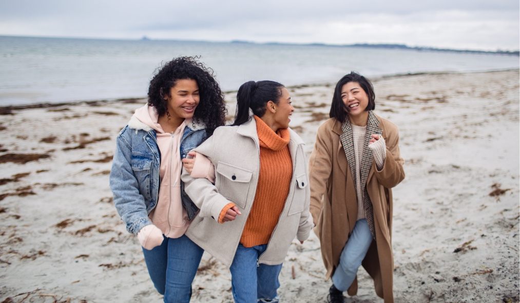 winter diverse friends walking alongside winter beach