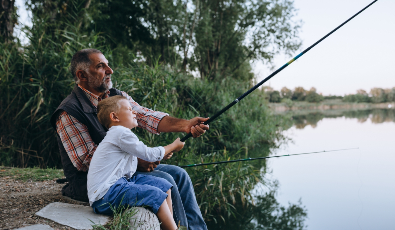boy fishing with his grandfather by the lake
