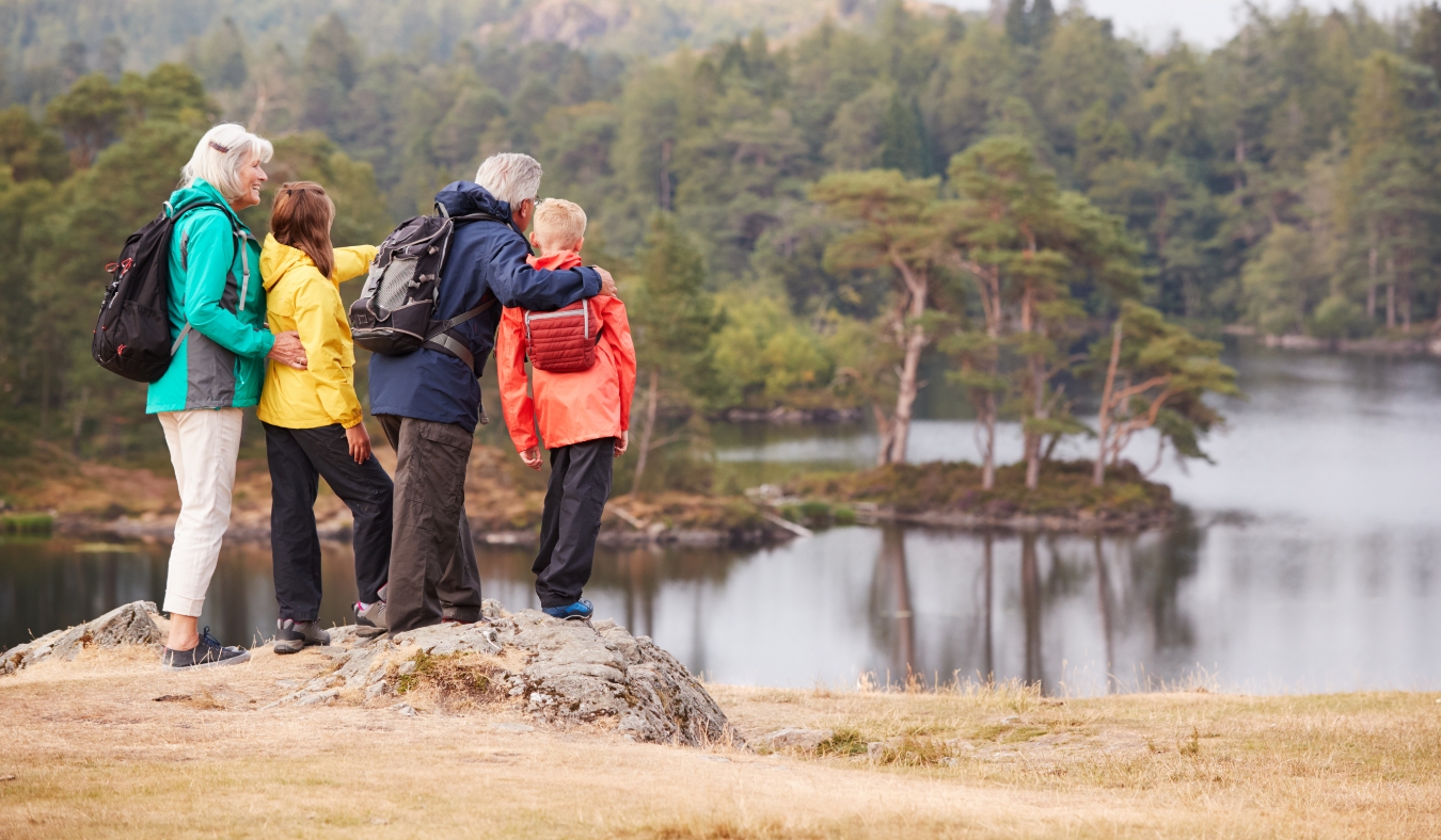 Grandparents and grandchildren standing on a rock admiring the view of a lake