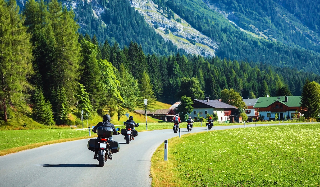 Group of motorcyclists on the road pass across mountainous village
