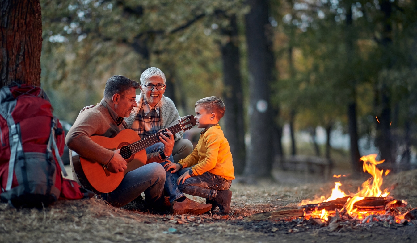 Male child with grandparents on picnic playing guitar