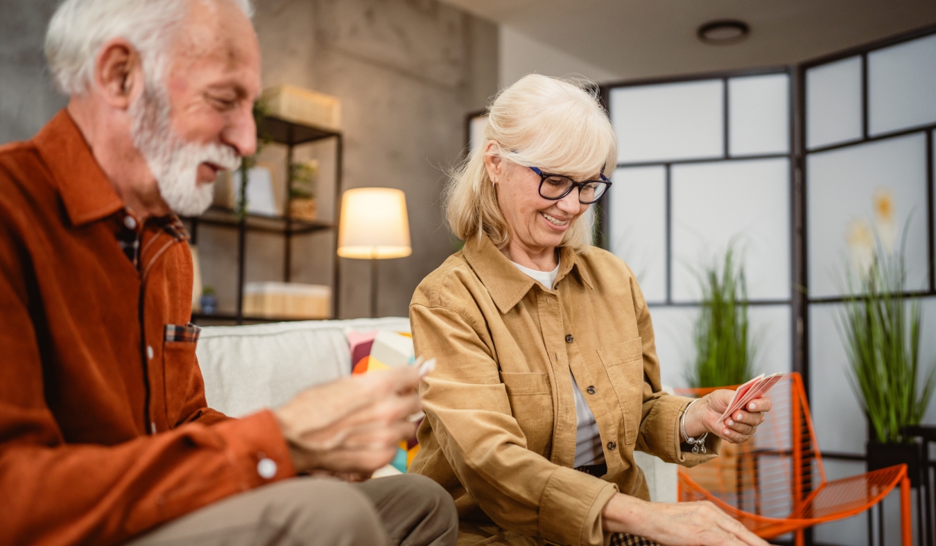 senior couple husband and wife play cards at home in bright day