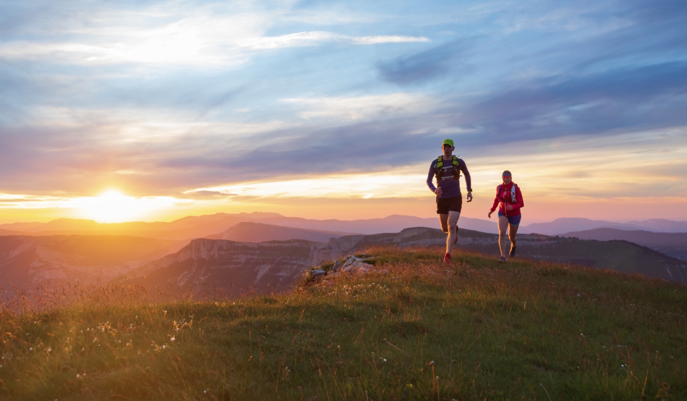 Two people trail running in the hills during a beautiful sunset