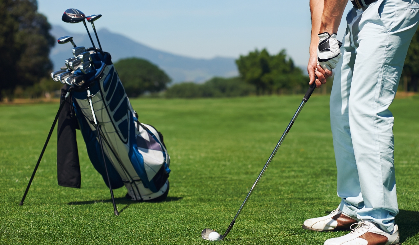 golfer man hitting golf ball from green fairway