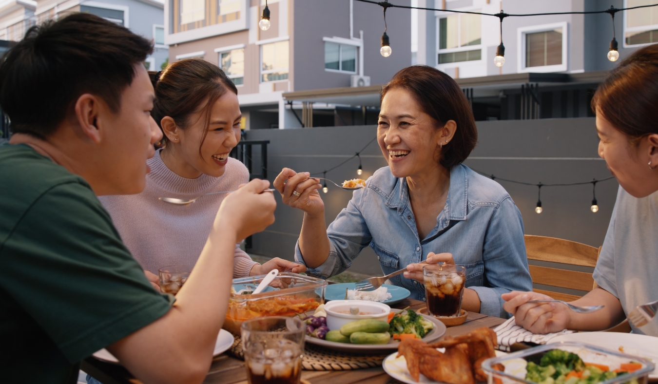 group of asian friends enjoying meal on patio