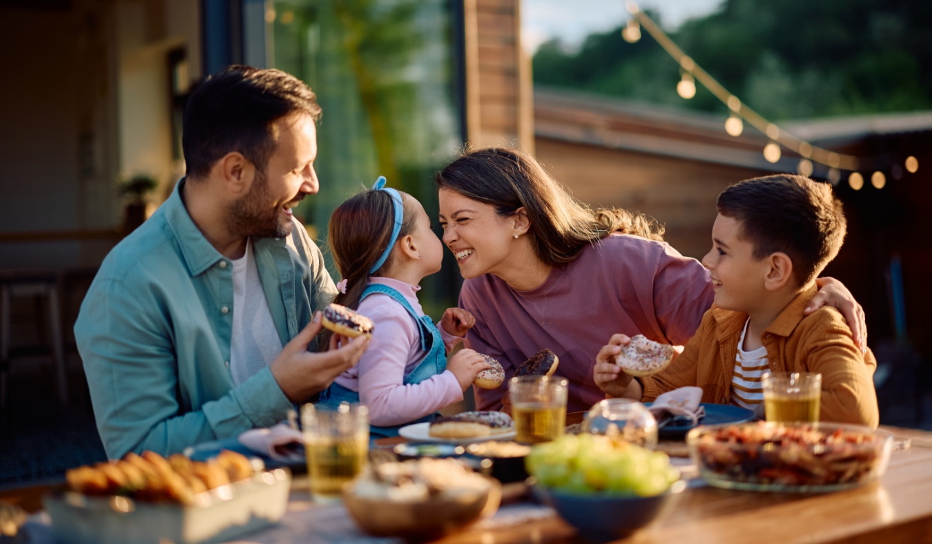 Happy family having fun while eating at dining table on a patio