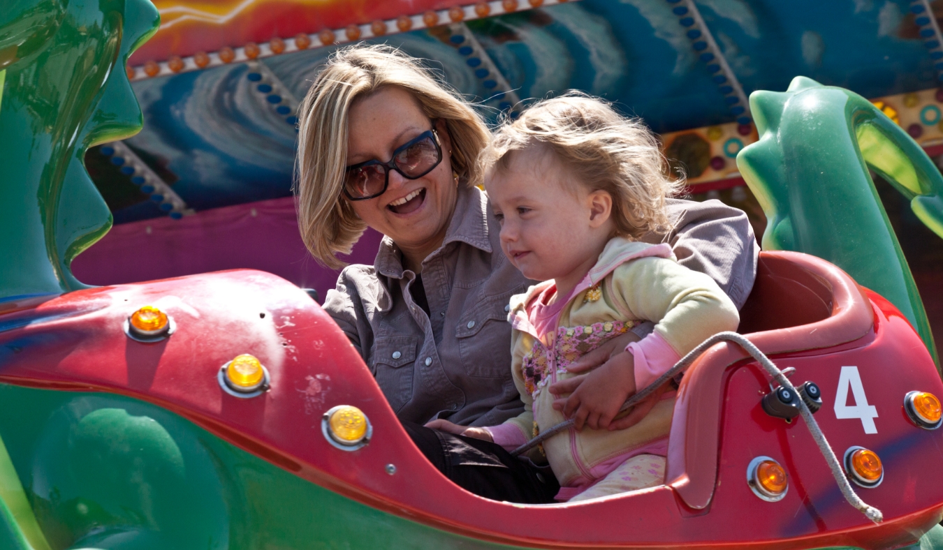 Mother and little daughter having fun rinding on carousel