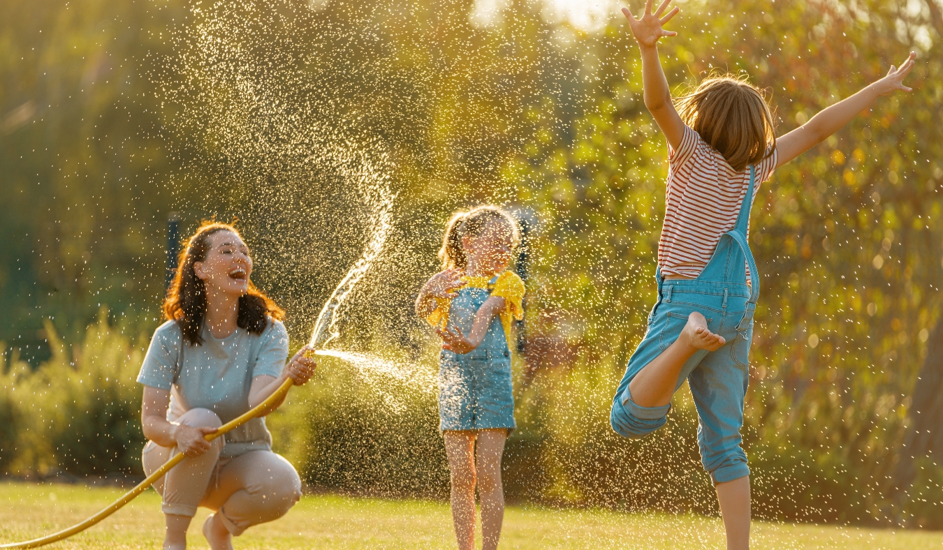 Mother sprinkling her kids in hot summer day