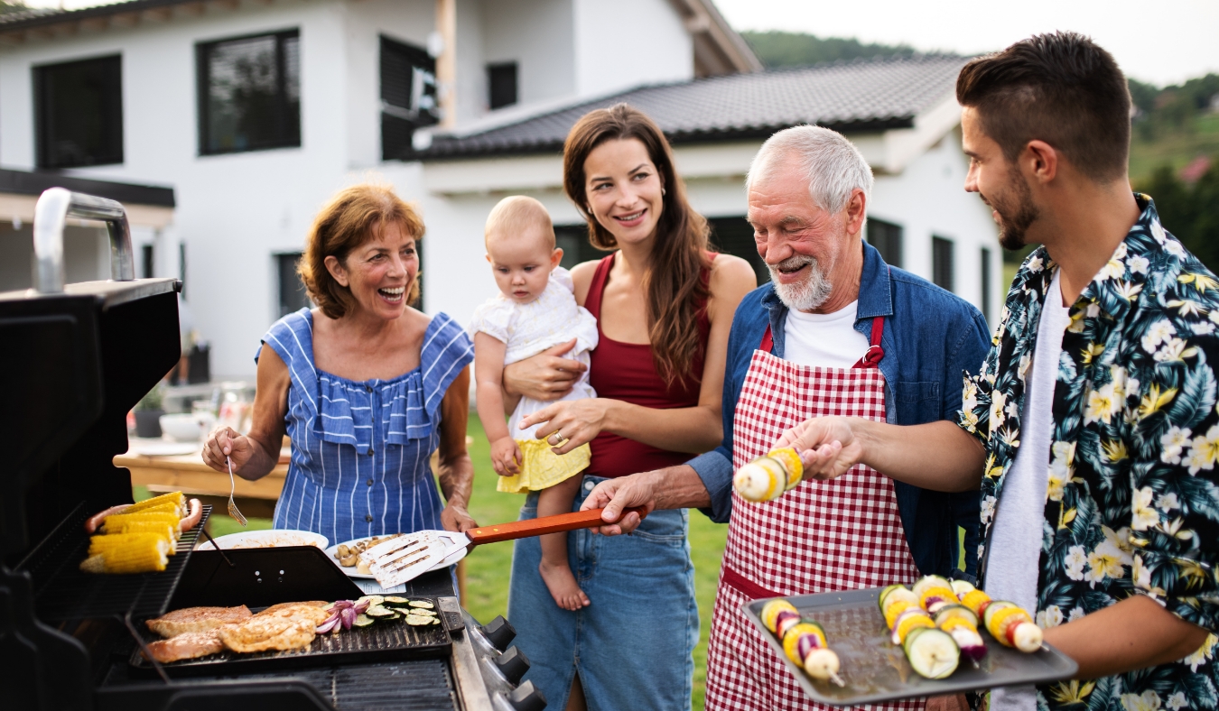 multigeneration family outdoors on garden barbecue grilling