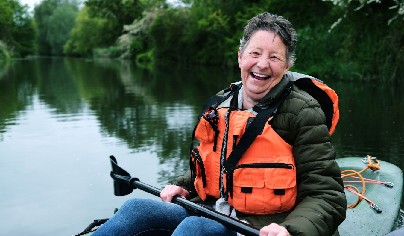 older woman laughing kayaking on water during summer