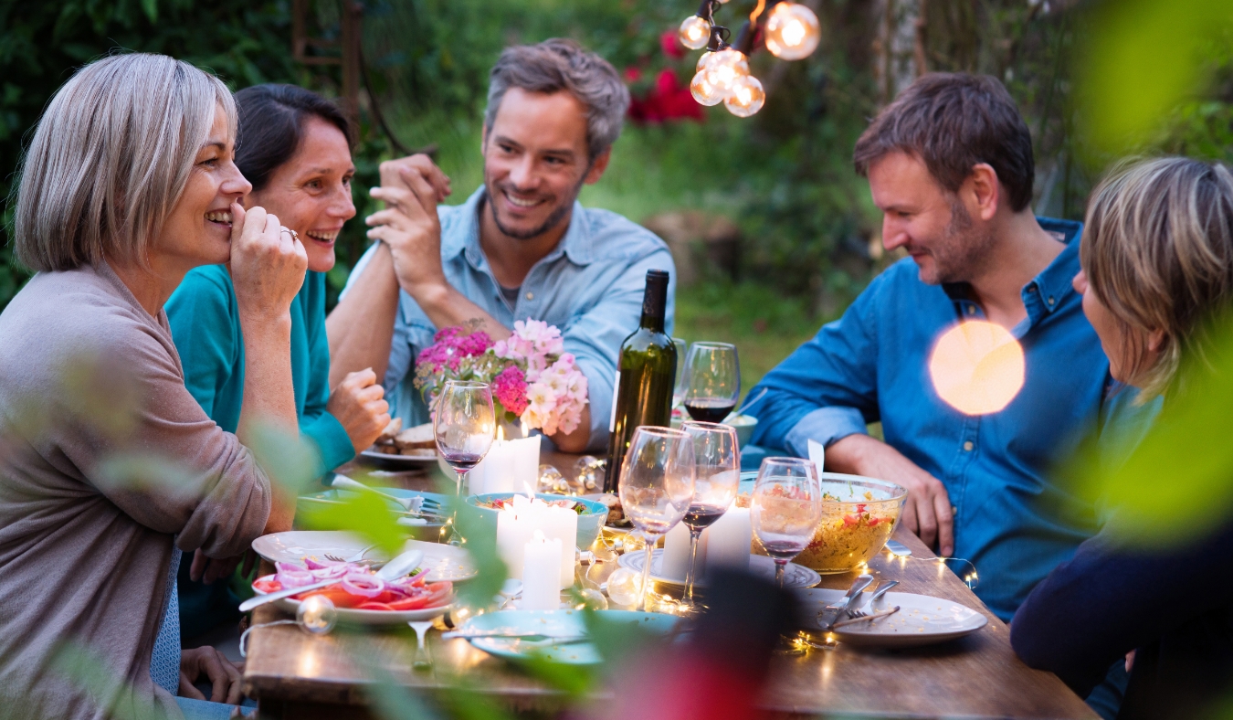 riends gathered around a table in a garden on a summer evening