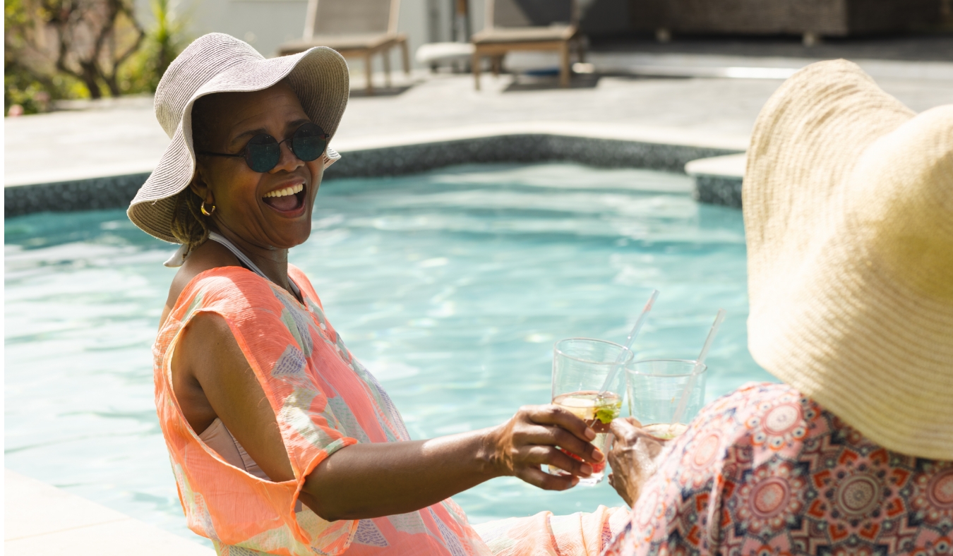 Senior African American woman in a sunhat laughs by the pool
