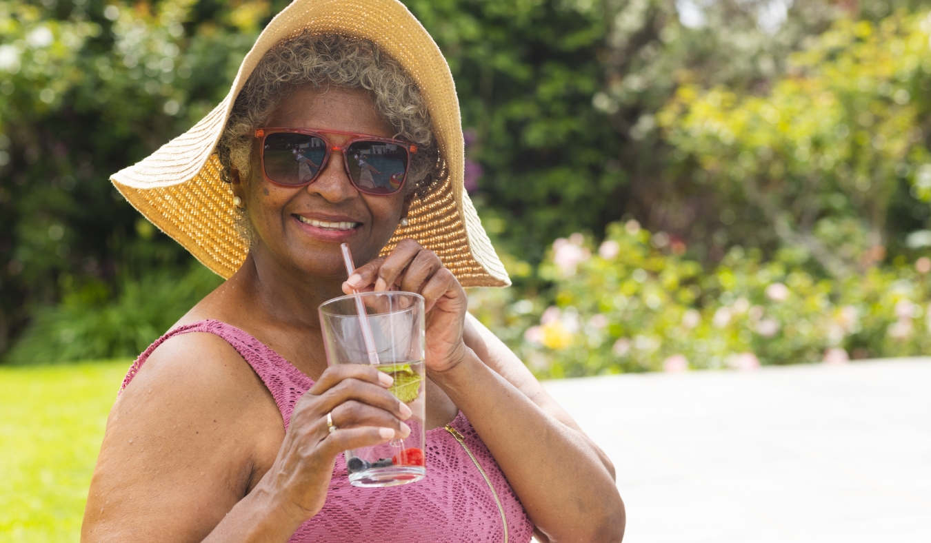 Senior biracial woman enjoys a drink by the poolside