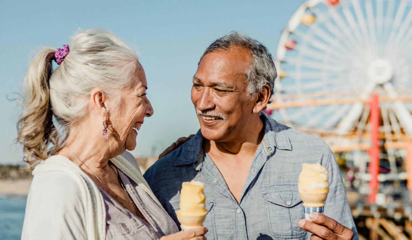 Smiling senior couple having ice cream at pier