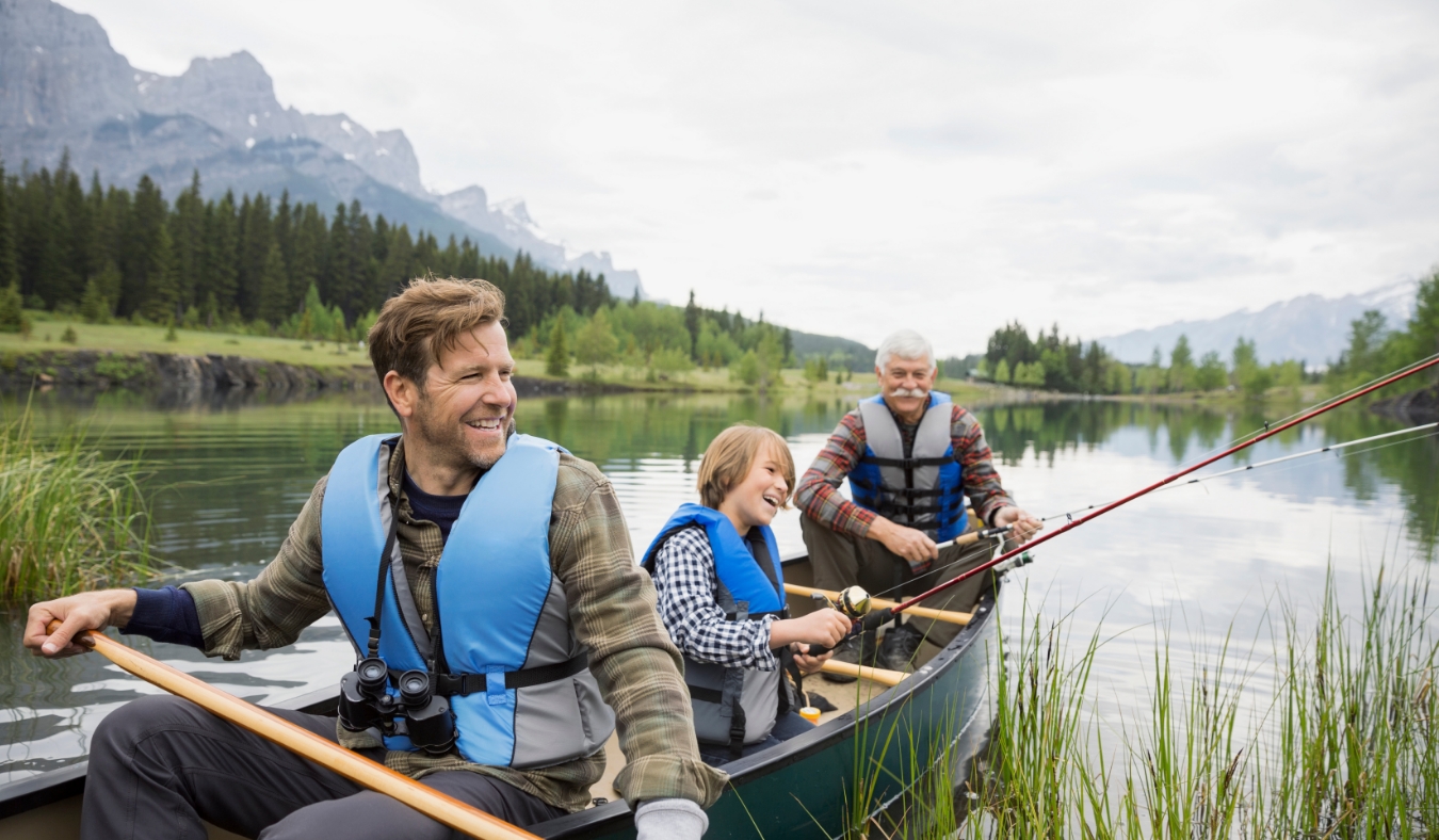 Three generations of men fishing in lake