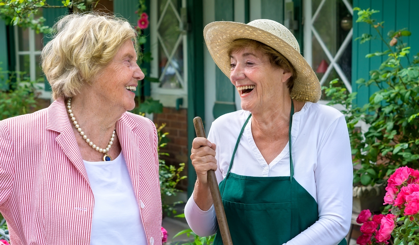 Two Senior Women Having Enjoyable Conversation and Laughing in Home Garden