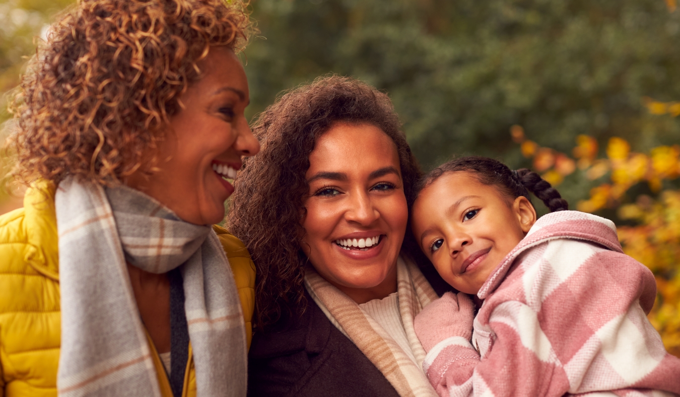 grandmother daughter and granddaughter on walk in autumn leaves park