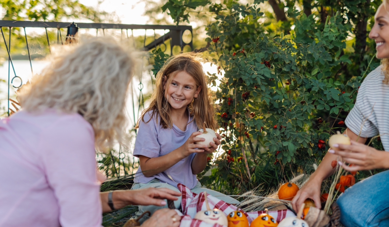 grandmother mother and granddaughter are decorating pumpkins