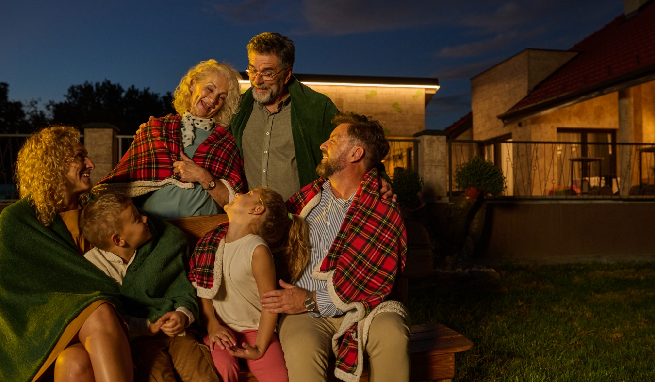 grandparents smiling down at family during chilly autumn evening