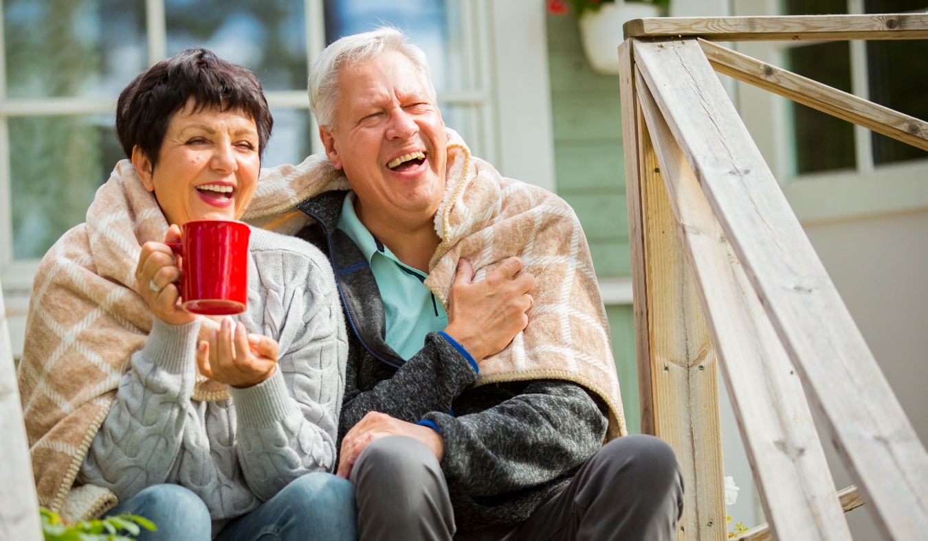 mature couple sitting on porch and drinking hot tea from mug