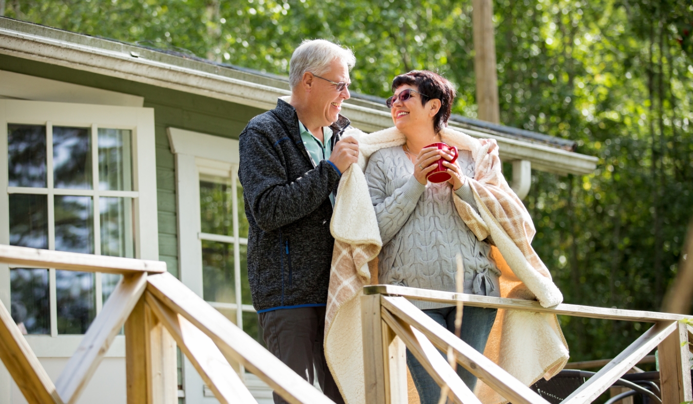 mature couple standing on porch and drinking hot drinks