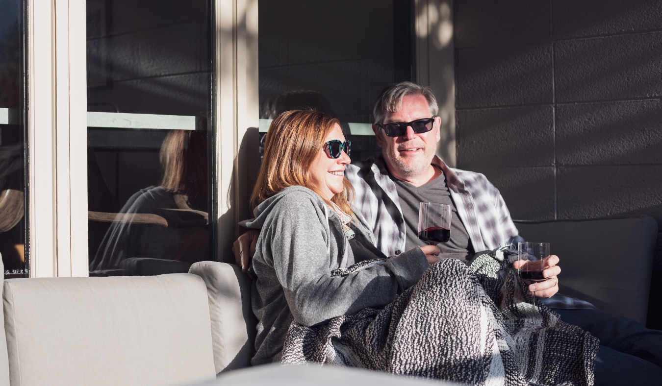 older married couple enjoying drinks snuggled on patio