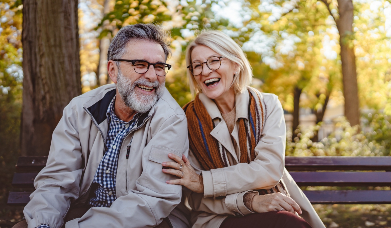 senior couple sitting on a park bench in autumn