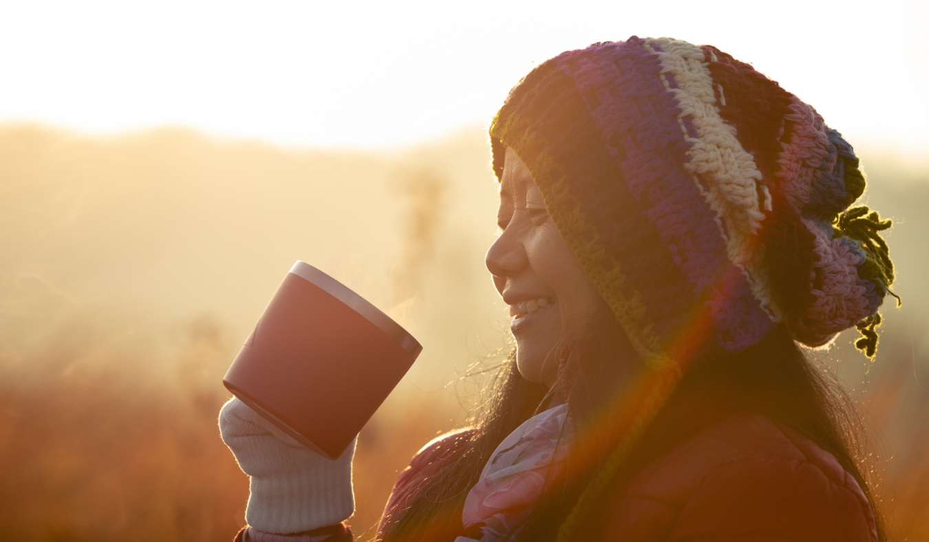 asian middle aged woman smiling happily while drinking coffee in the morning
