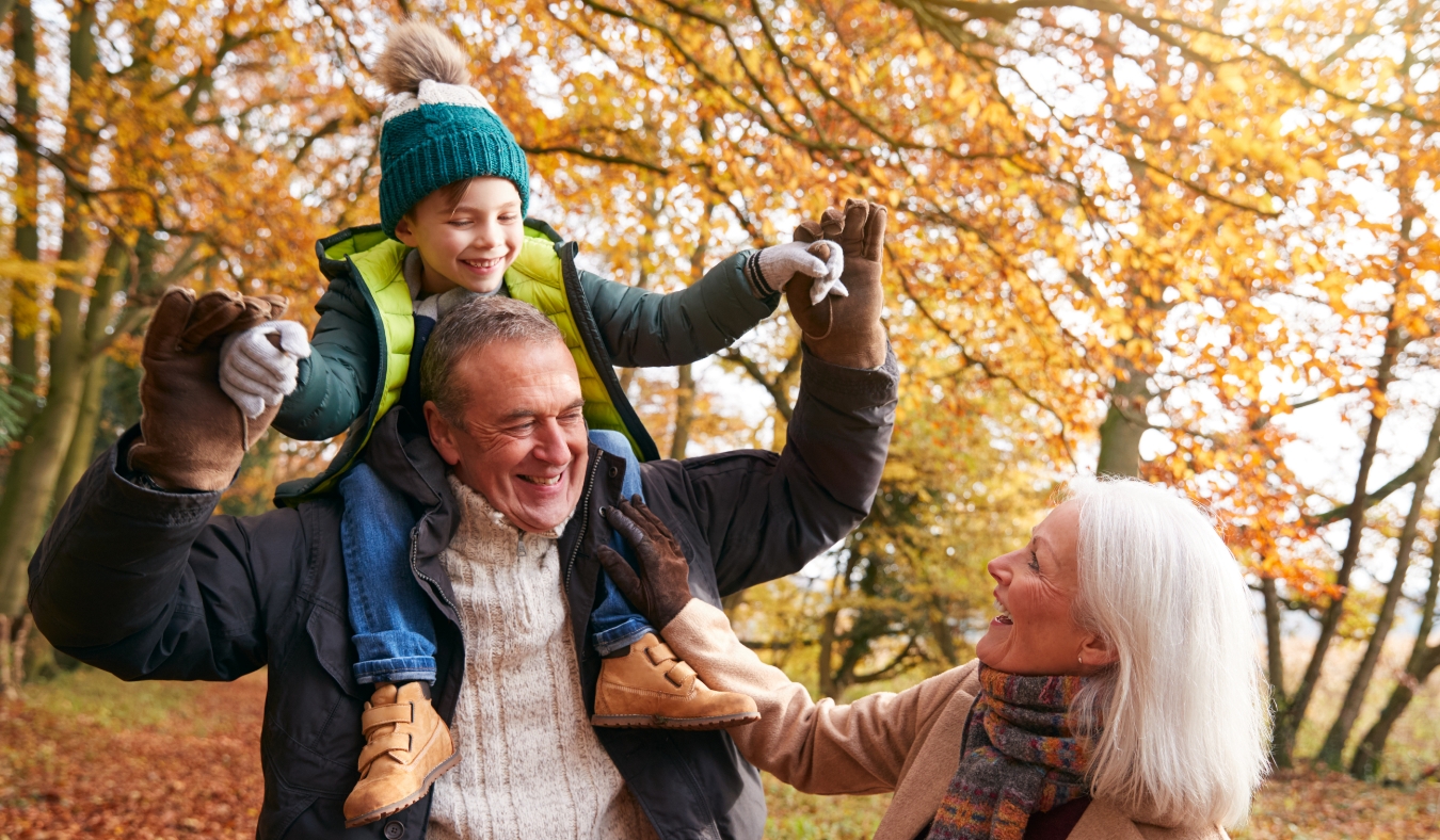 multi generation family playing in park during autumn weather