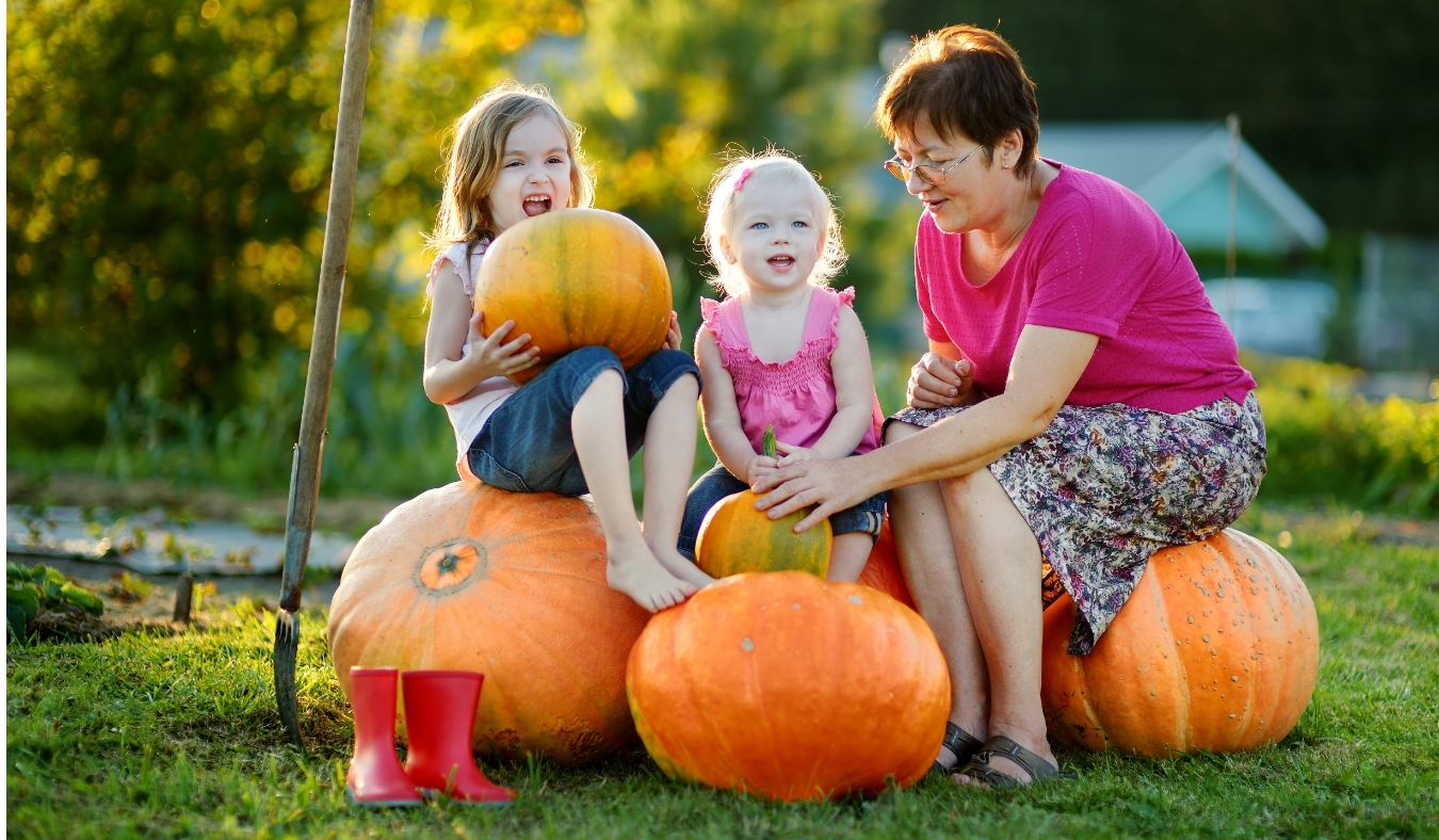 grandmother sitting on pumpkins with two granddaughters