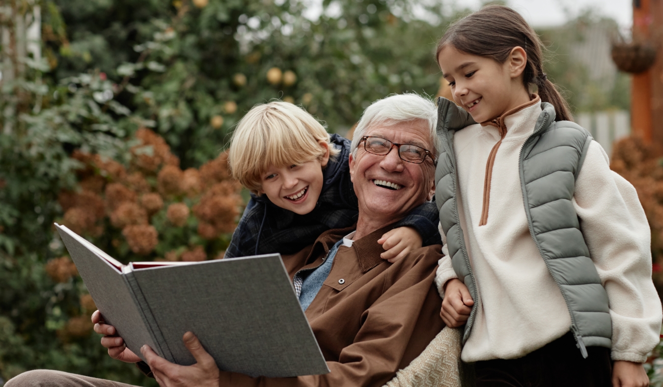 grandpa reading to grandchildren outside in fall