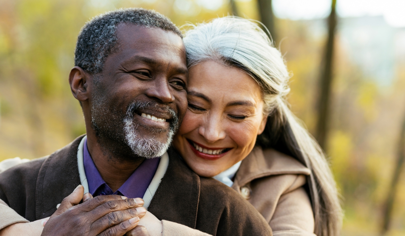 middle aged diverse couple smiling hugging outside