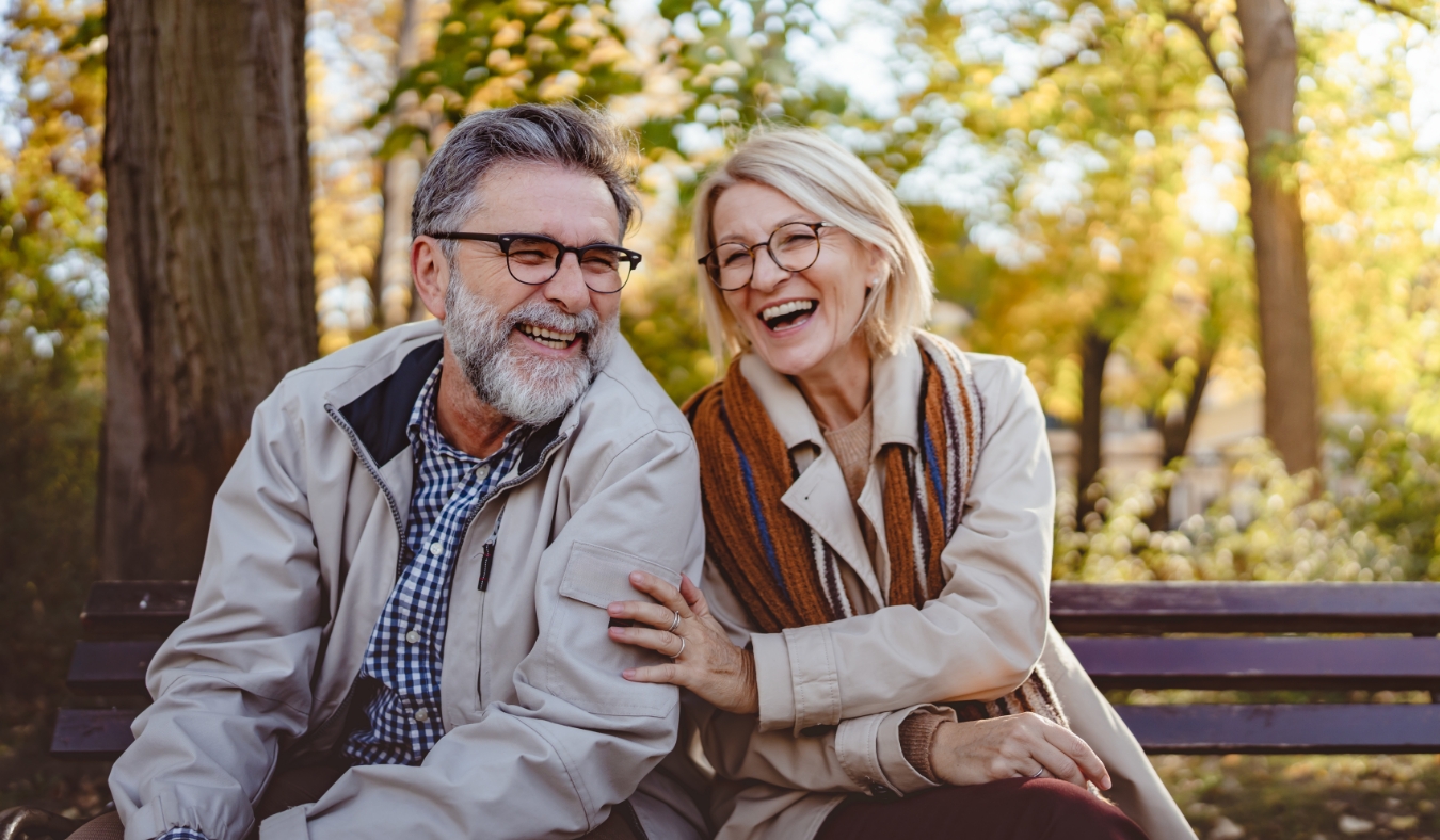 senior couple on autumn bench laughing together