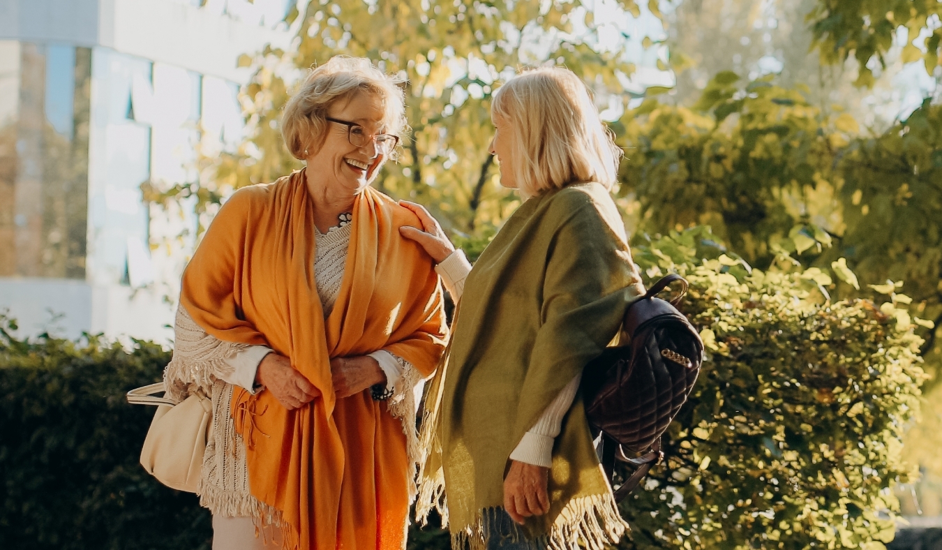 senior woman smiling with friend outside during autumn