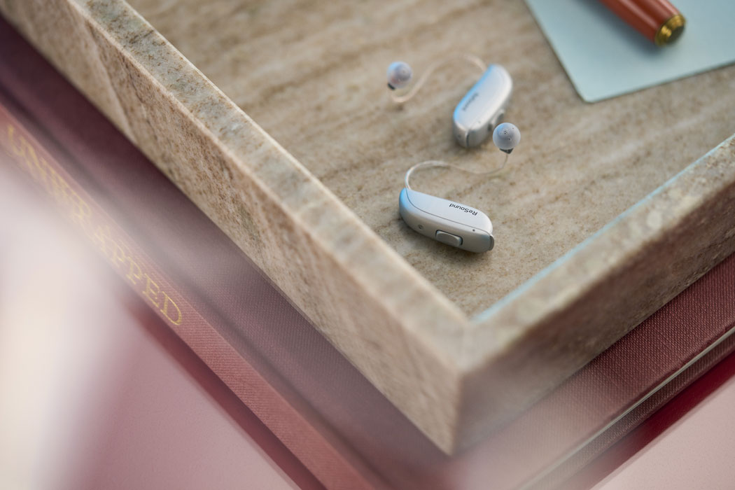 ReSound Vivia lifestyle hearing aids on desk corner lifestyle silver