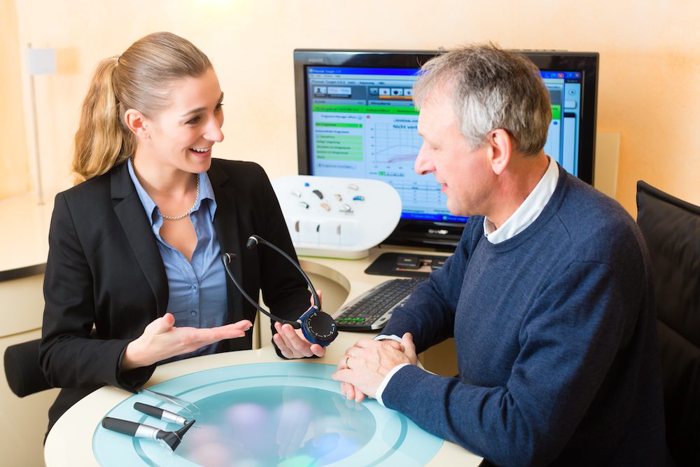 audiologist discussing patient's audiogram in office