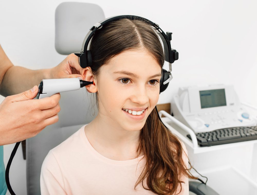 young girl having her ears tested by hearing specialist