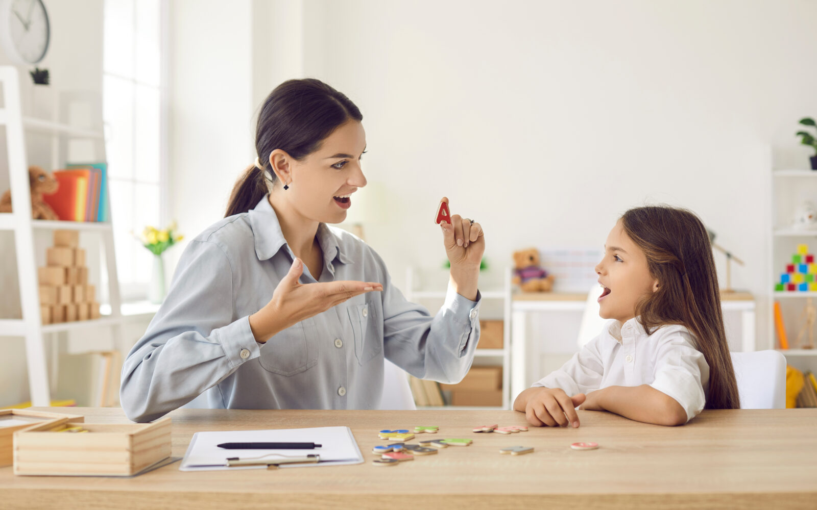 Speech language pathologist helping child learn letters and overcome speech problems
