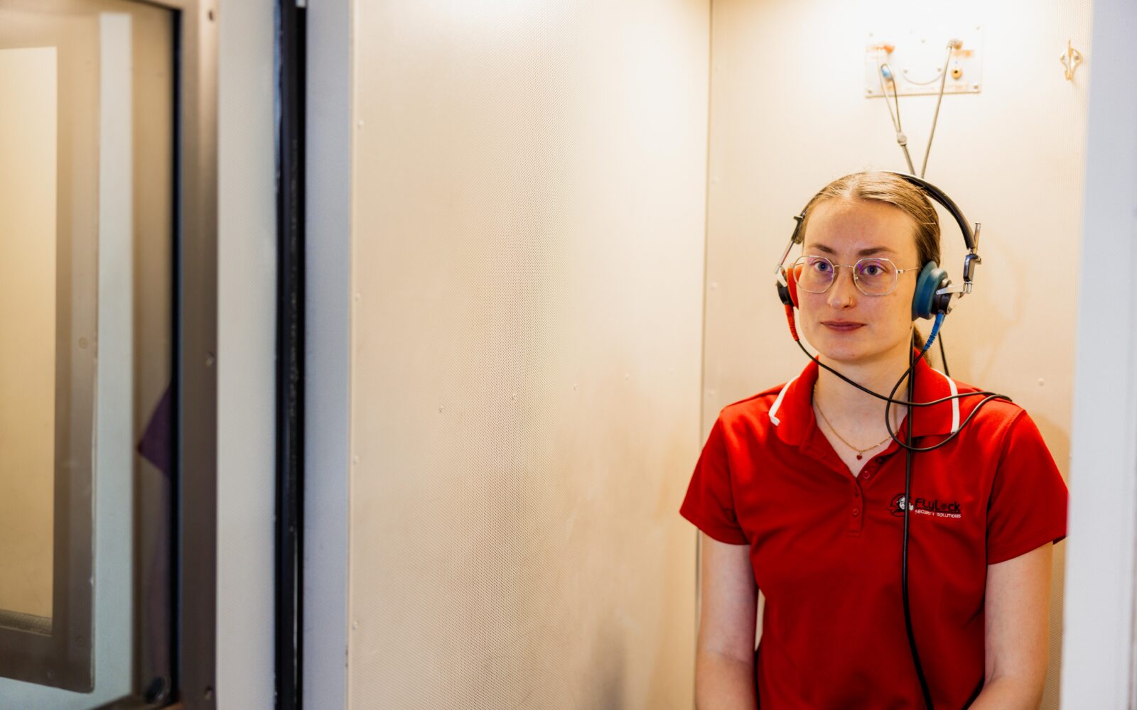 Woman inside a hearing booth participating in a hearing screening