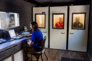 Two men having a hearing screening while another man runs the tests