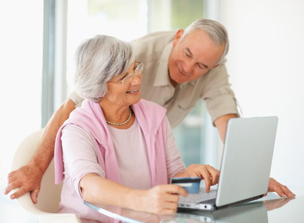 a couple standing over a laptop while researching new hearing aids