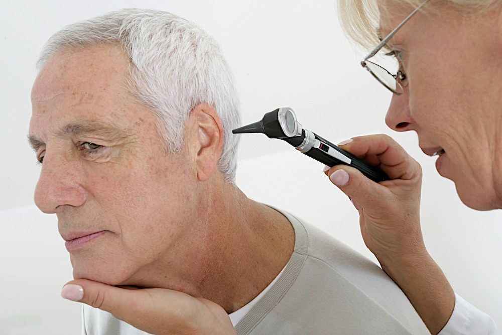 audiologist looking into the ear of her senior hearing loss patient